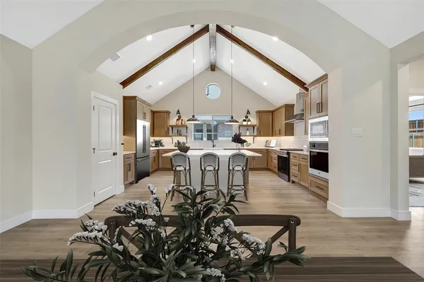 a kitchen with stainless steel appliances granite countertop a sink a stove top oven a cabinetry and chairs