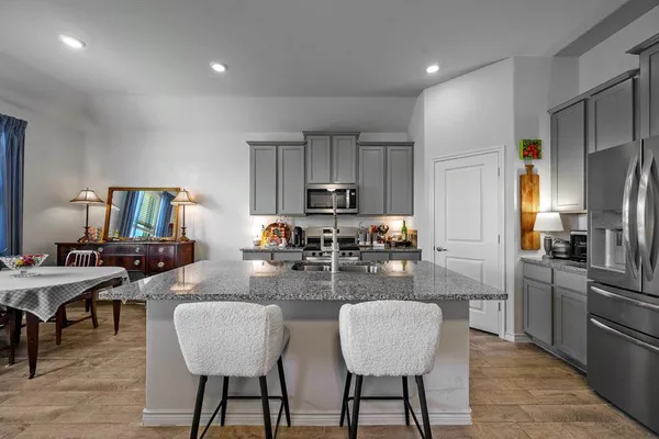 a kitchen with sink refrigerator dining table and chairs