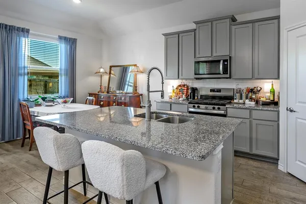 a kitchen with stainless steel appliances granite countertop a stove a sink dishwasher a dining table and chairs with wooden floor