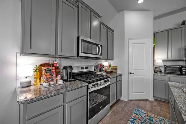 a kitchen with stainless steel appliances granite countertop a stove a sink and a microwave