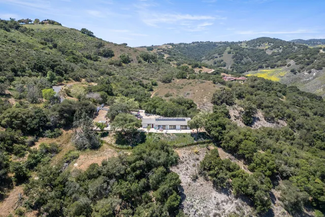 an aerial view of residential houses with outdoor space and trees