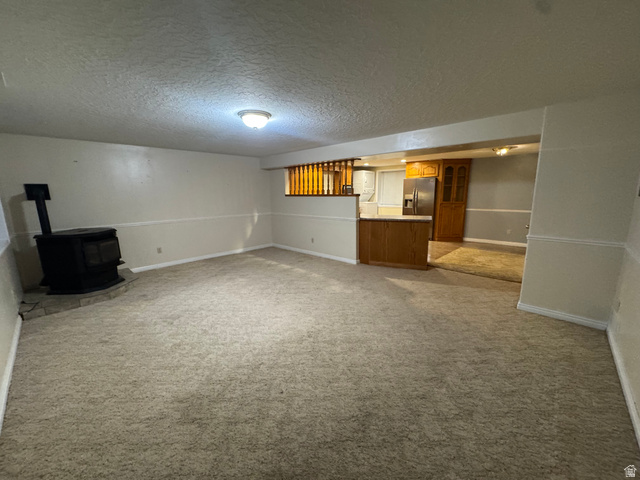 655 North 8th East Preston, ID 83263 - Photo 15 of 32 Unfurnished living room with a wood stove, a textured ceiling, and light carpet