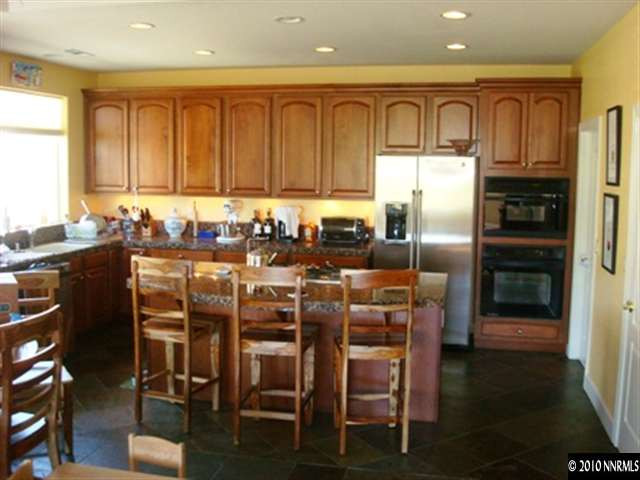 7005 Cour Street Reno, NV 89511 - Photo 3 of 9 a kitchen with a table chairs refrigerator and cabinets