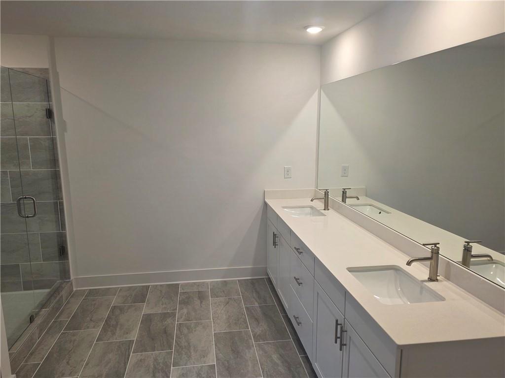 221 Brownlee Road Woodstock, GA 30188 - Photo 18 of 33 a bathroom with a double vanity sink a mirror and a shower