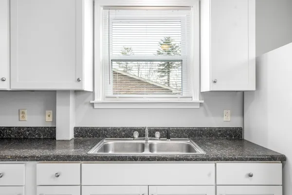 a kitchen with granite countertop white cabinets and a sink