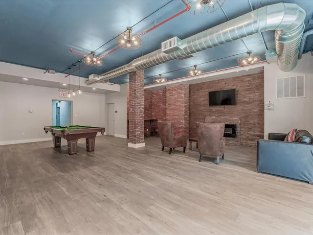 a room with pool table wooden floor and windows