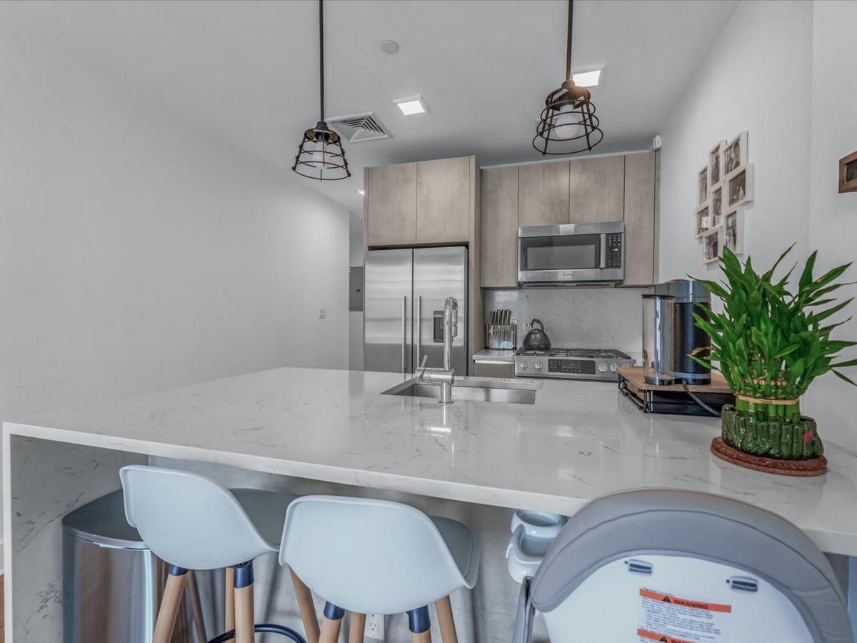 21-10 44th Drive, Unit 2B Queens, NY 11101 - Photo 6 of 19 a kitchen with kitchen island a stove and a chandelier