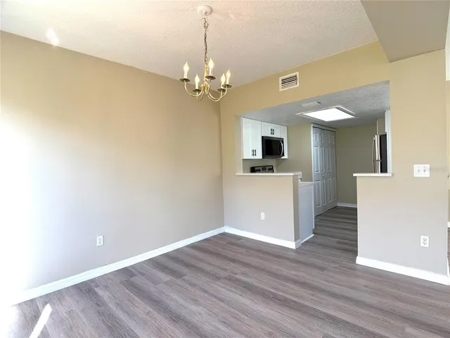 a view of a kitchen with an empty room and wooden floor