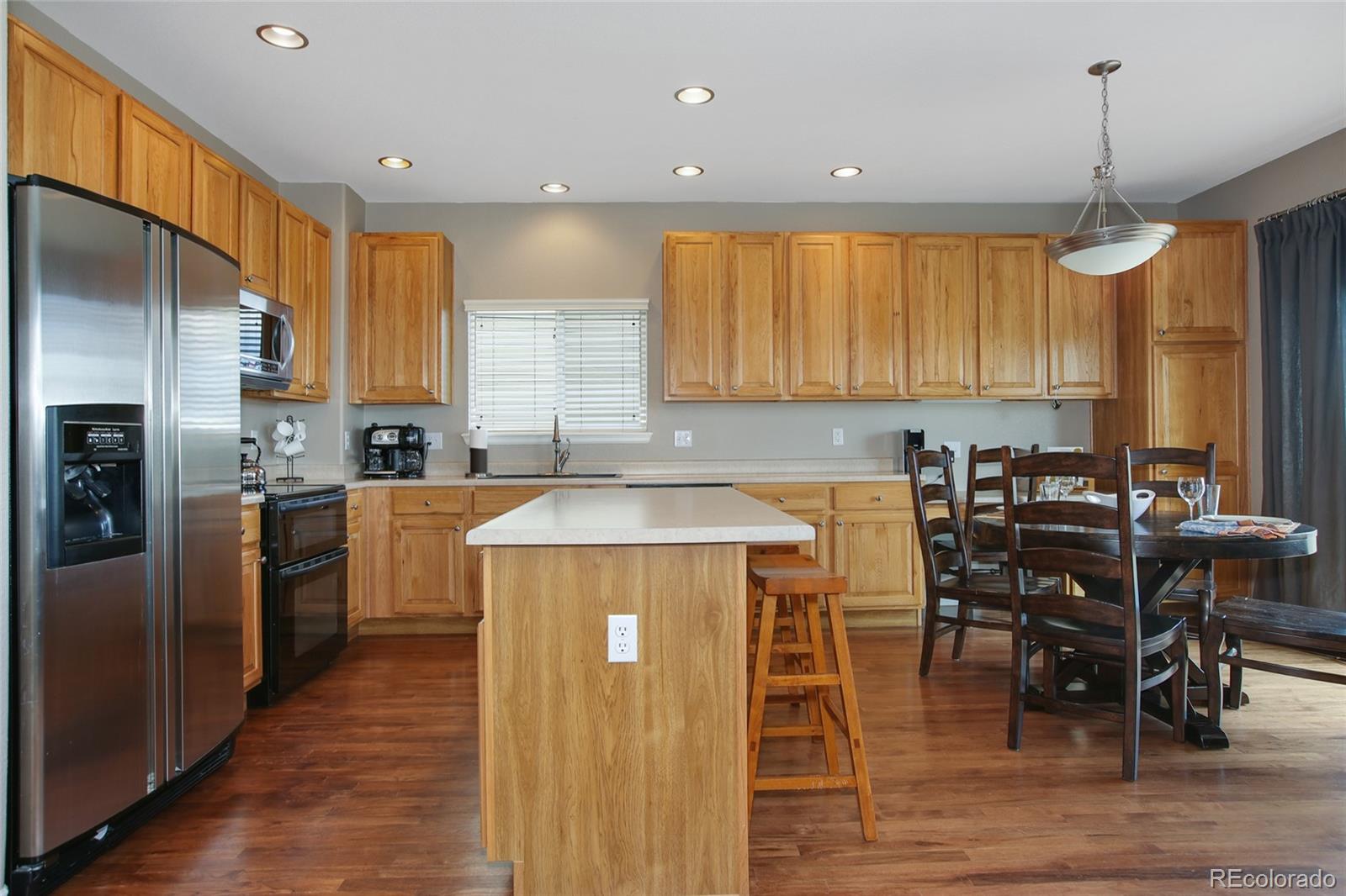 10274 Willowbridge Court Highlands Ranch, CO 80126 - Photo 11 of 35 a kitchen with stainless steel appliances kitchen island granite countertop a table chairs and a refrigerator
