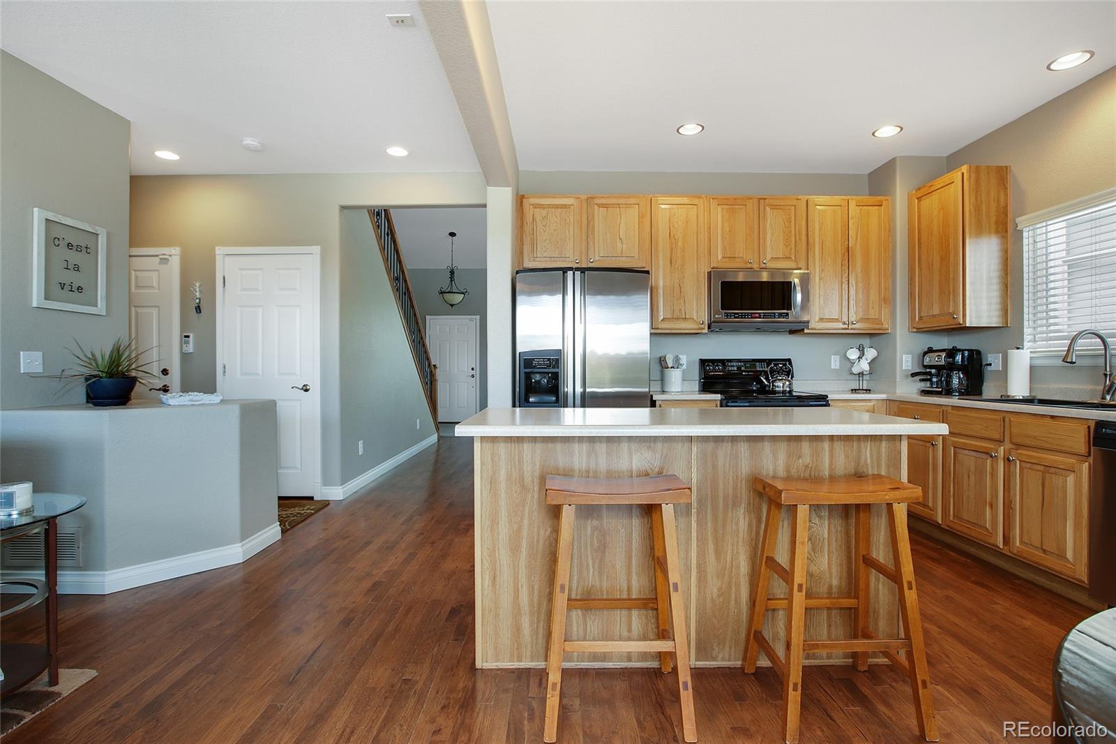 10274 Willowbridge Court Highlands Ranch, CO 80126 - Photo 10 of 35 a kitchen with kitchen island granite countertop wooden floors white cabinets and stainless steel appliances