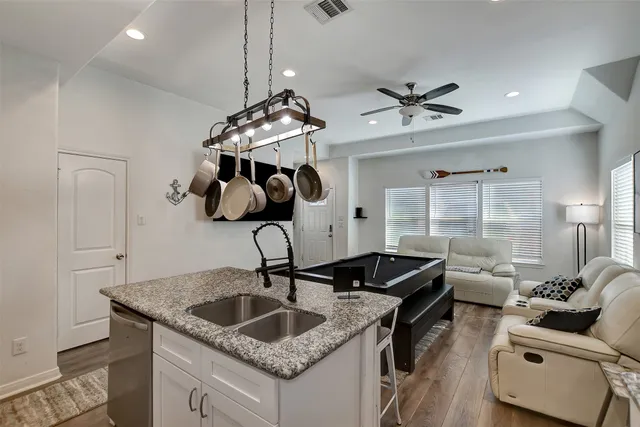 a kitchen with granite countertop a sink a counter top space and living room view