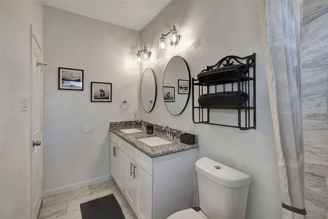 a bathroom with a granite countertop sink a toilet and a mirror