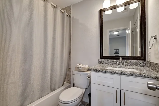 a bathroom with a granite countertop sink vanity mirror and toilet