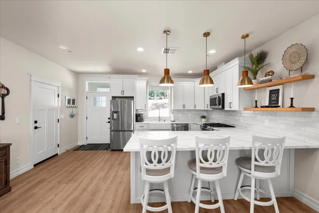 a kitchen with stainless steel appliances granite countertop a stove and chairs