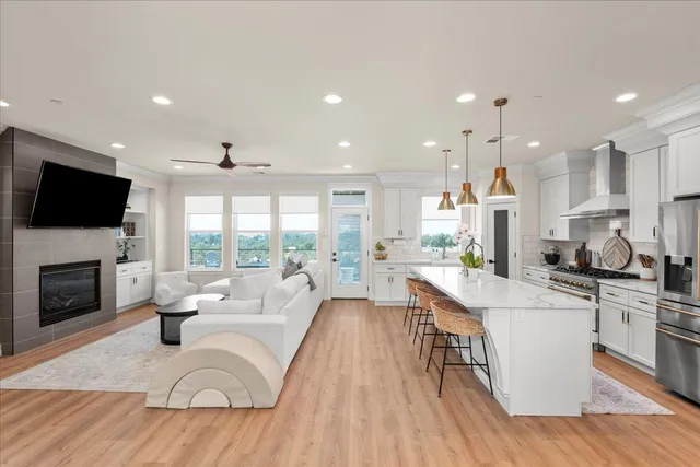 a living room with stainless steel appliances furniture fireplace and a flat screen tv