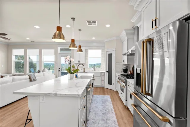 a kitchen with stainless steel appliances a refrigerator a sink a stove and white cabinets