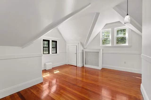 an empty room with wooden floor chandelier and windows