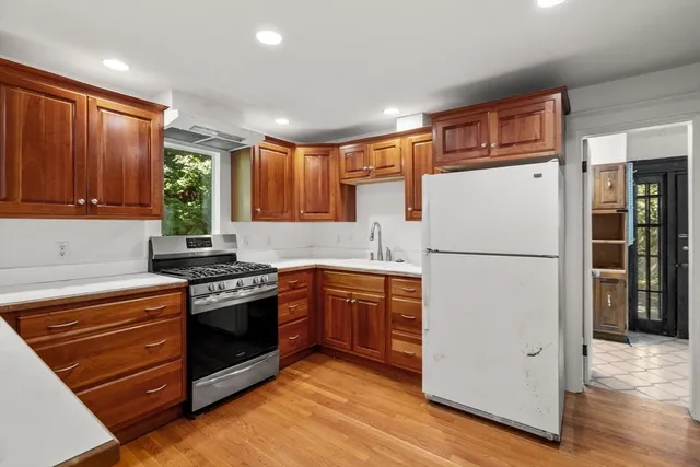 a kitchen with stainless steel appliances granite countertop a refrigerator stove a sink dishwasher and wooden cabinets with wooden floor