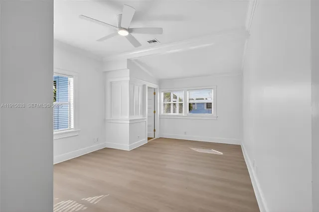 an empty room with windows and ceiling fan