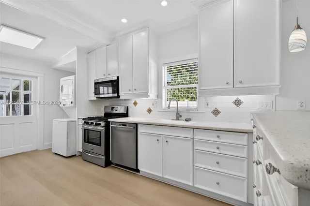 a kitchen with white cabinets stainless steel appliances and sink