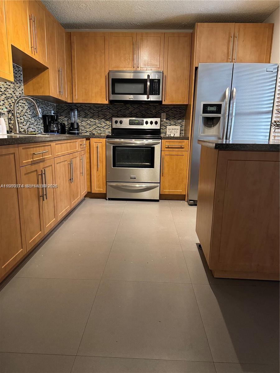 1226 North Hiatus Road, Unit 1226 Pembroke Pines, FL 33026 - Photo 4 of 10 a kitchen with stainless steel appliances granite countertop a refrigerator a stove a sink and a microwave