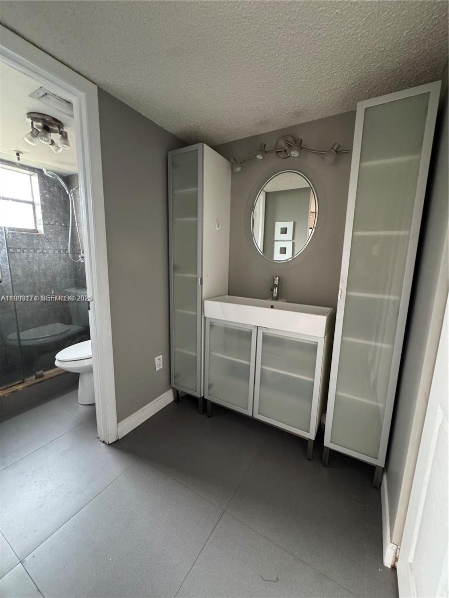 1226 North Hiatus Road, Unit 1226 Pembroke Pines, FL 33026 - Photo 7 of 10 a bathroom with a toilet a sink and mirror