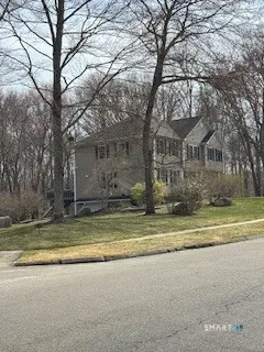 a view of a house with a yard and large trees