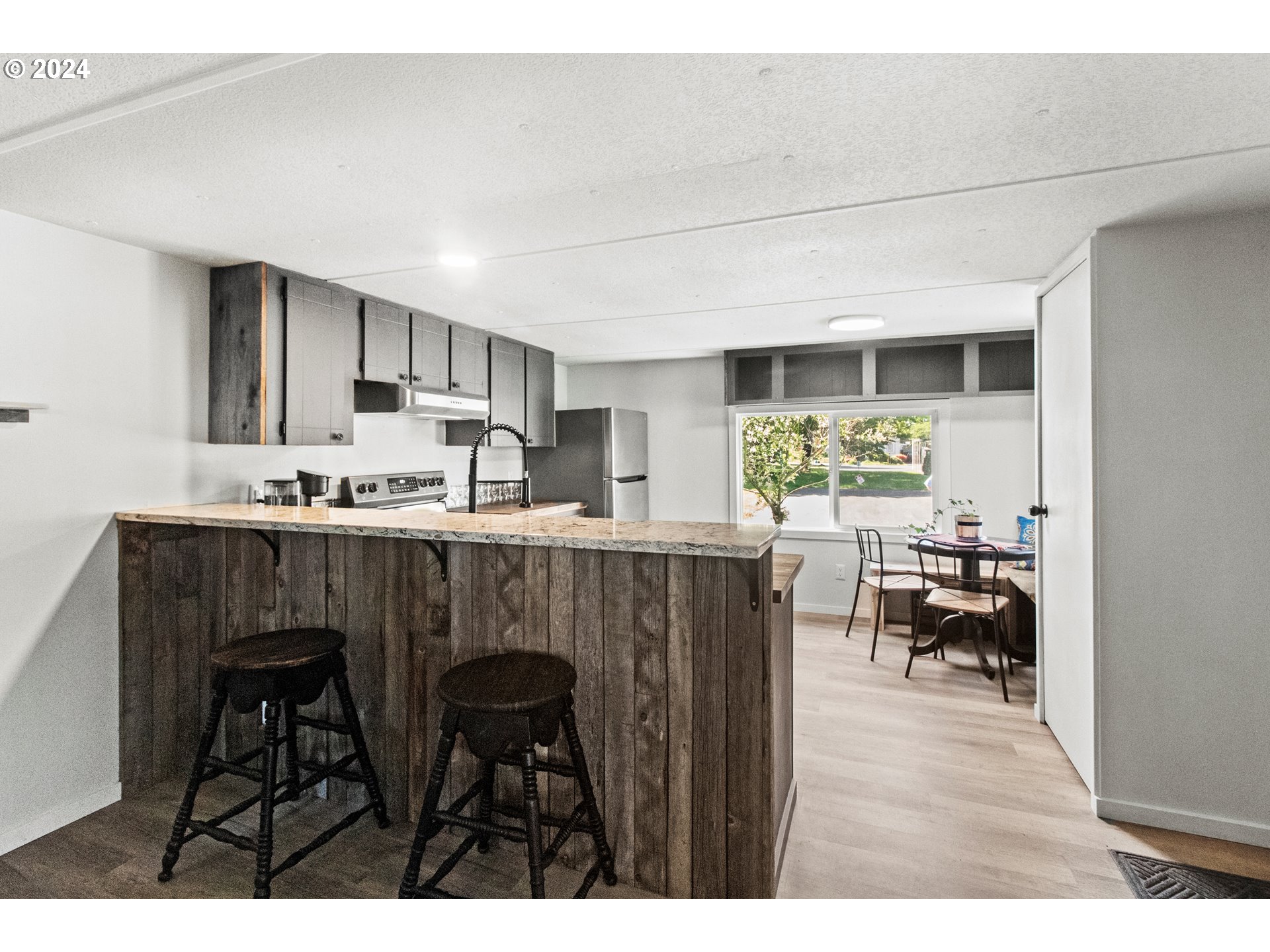 1400 Candlelight Drive, Unit 185 Eugene, OR 97402 - Photo 19 of 46 a kitchen with a table chairs refrigerator and cabinets