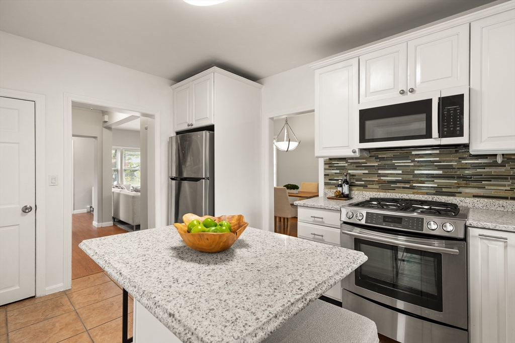 93 Bay State Road Methuen, MA 01844 - Photo 9 of 23 a kitchen with stainless steel appliances kitchen island granite countertop a stove refrigerator and microwave