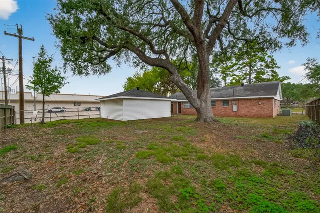 a view of a house with a yard and a large tree