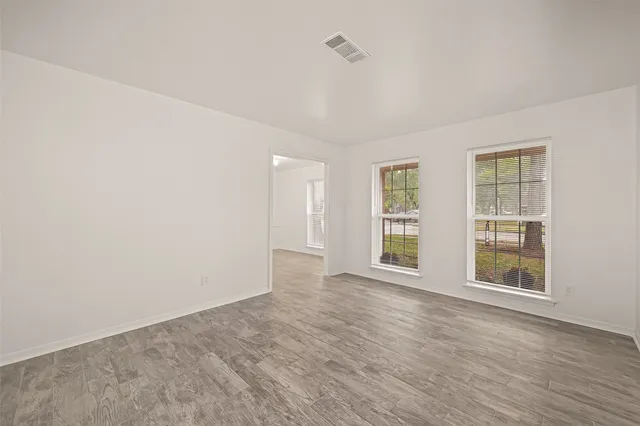 an empty room with wooden floor and windows