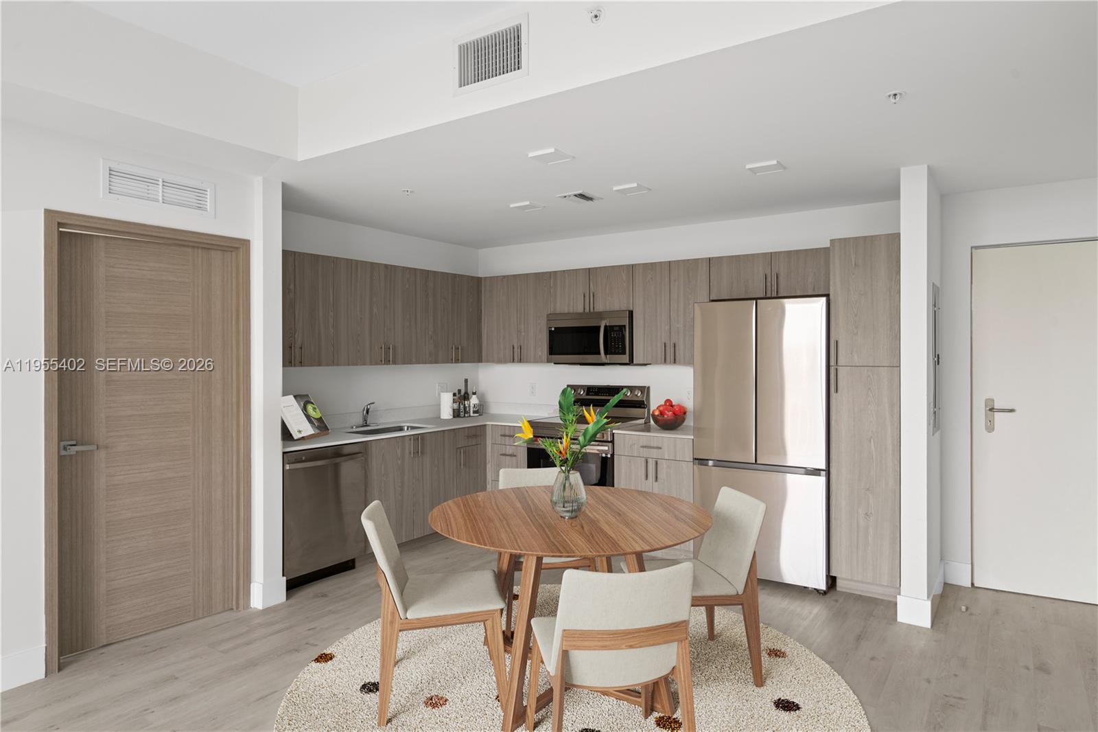 1601 Southwest 32nd Avenue, Unit 513 Miami, FL 33145 - Photo 3 of 6 a kitchen with stainless steel appliances a dining table chairs refrigerator and microwave