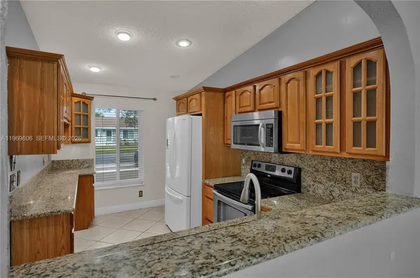 a kitchen with stainless steel appliances granite countertop a sink and a refrigerator