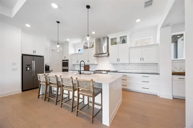 a kitchen with kitchen island granite countertop lots of white cabinets and stainless steel appliances