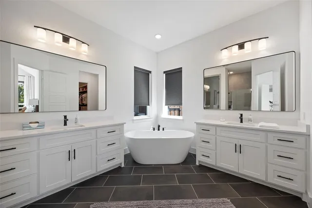 a spacious bathroom with a double vanity sink mirror and bathtub