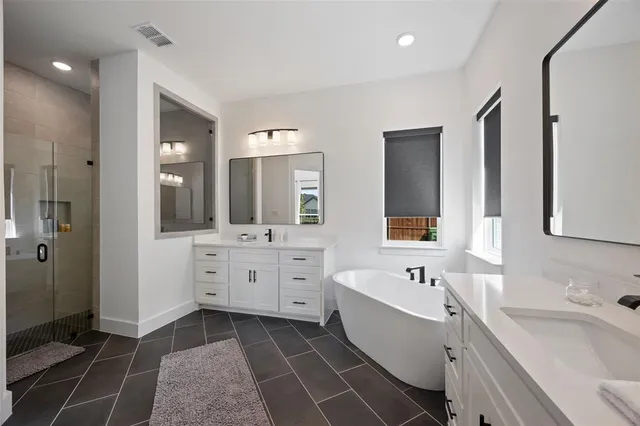 a bathroom with a double vanity sink mirror and bathtub