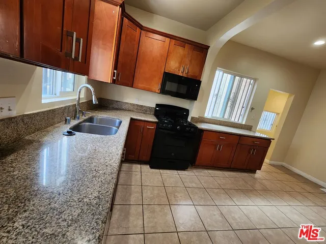 a large kitchen with a stove a refrigerator a sink a washer dryer and white cabinets