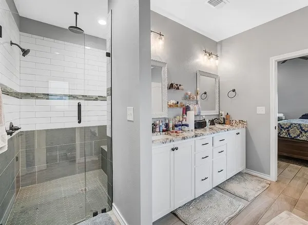a bathroom with a double vanity sink a mirror and shower