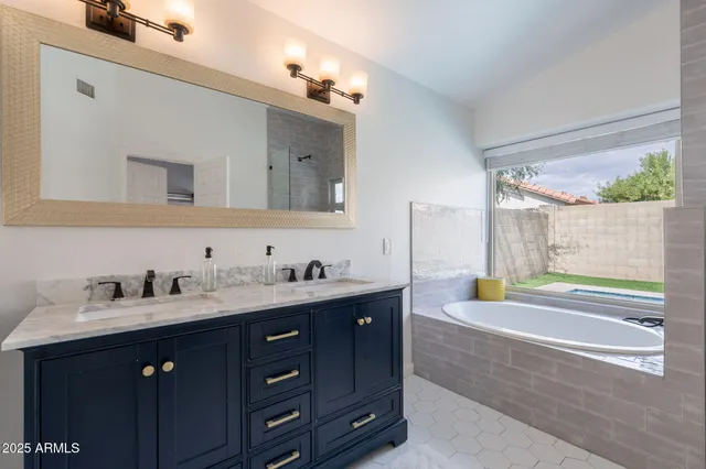 a bath room with a sink vanity granite tub shower and a mirror
