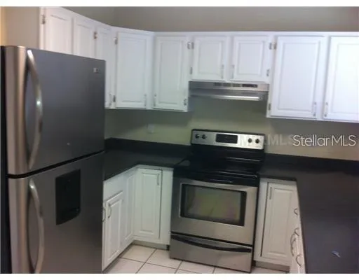 a kitchen with granite countertop white cabinets and stainless steel appliances