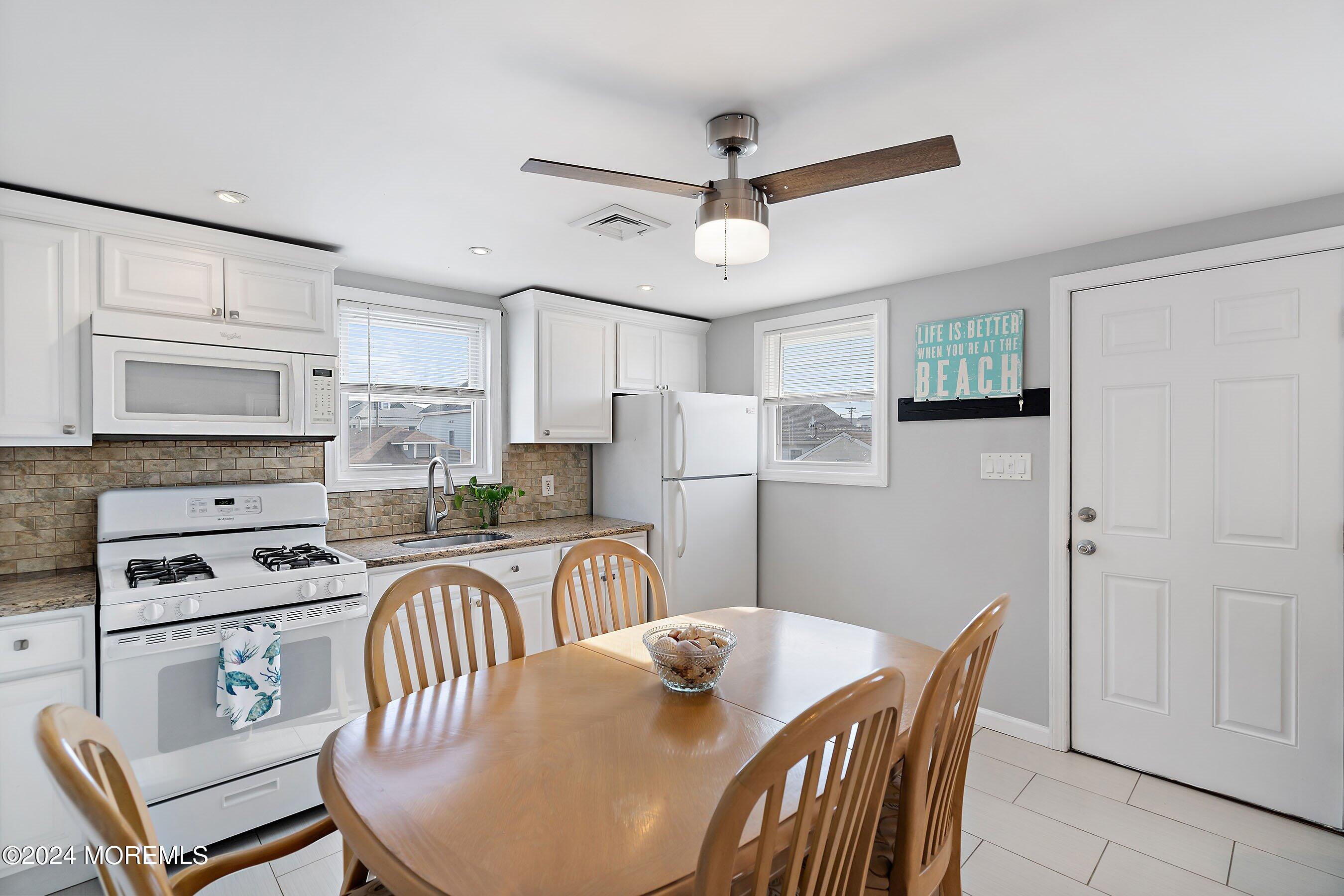 212 Randall Avenue Point Pleasant Beach, NJ 08742 - Photo 11 of 18 a kitchen with stainless steel appliances granite countertop a dining table chairs refrigerator and cabinets