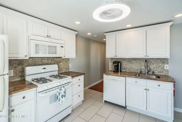 a kitchen with a stove a refrigerator and white cabinets