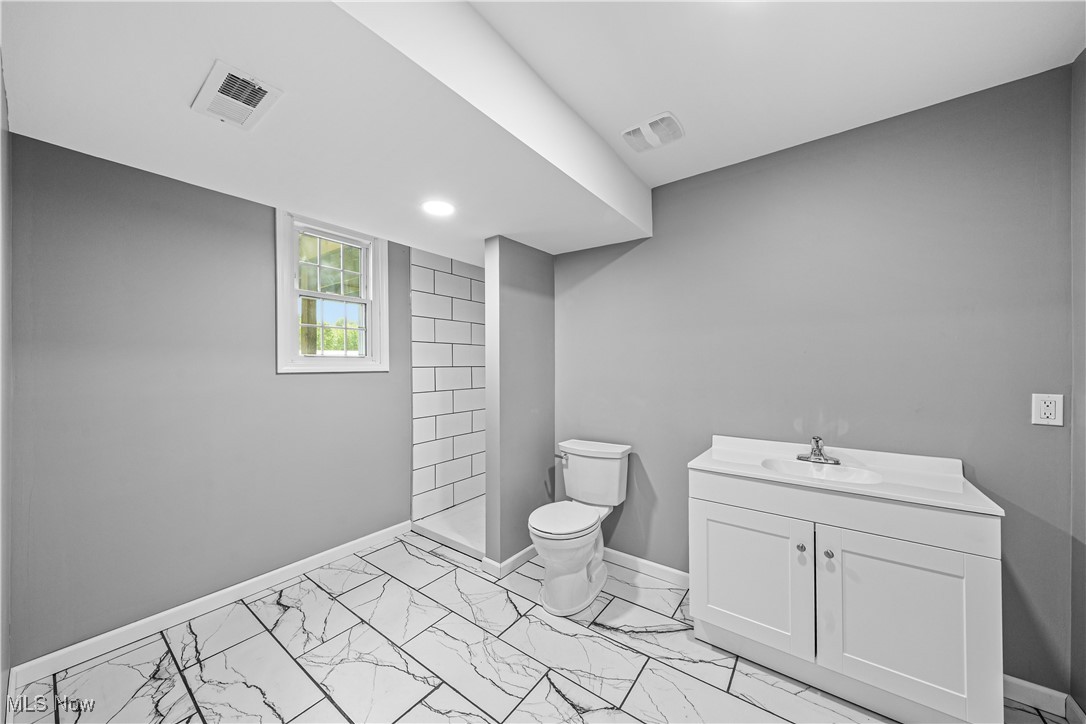 23595 Sandy Creek Road Minerva, OH 44657 - Photo 10 of 32 Bathroom with toilet, marble finish floors, baseboards, vanity, and tiled shower