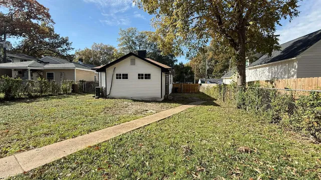 a view of a house with a yard and large trees