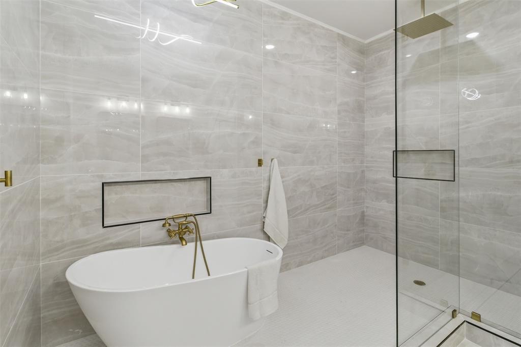 435 Waterboard Road Trinidad, TX 75163 - Photo 32 of 39 Contemporary bathroom featuring a freestanding soaking tub with brass fixtures, a walk-in shower with a glass enclosure and rainfall showerhead, and light-toned tile walls