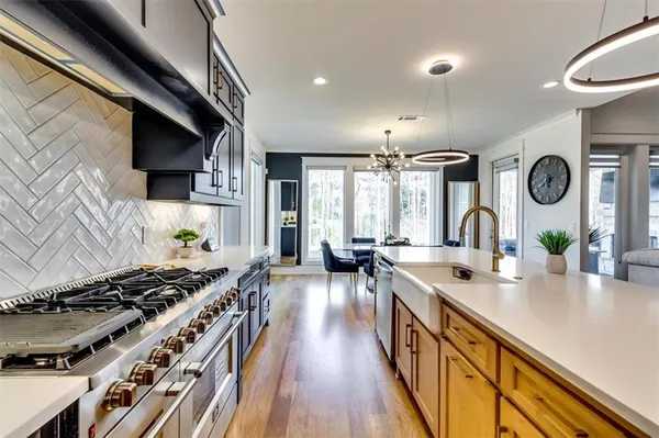 a kitchen with stainless steel appliances granite countertop a sink a stove and a wooden floors