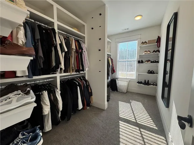 a view of walk in closet with clothes and shoes