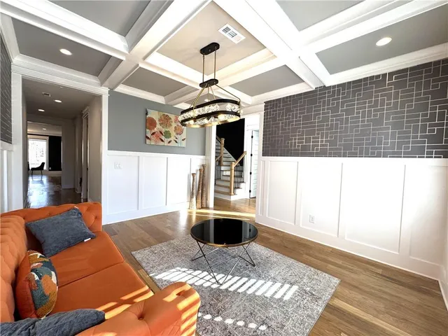 a kitchen with stainless steel appliances granite countertop a stove a refrigerator a sink a dining table and chairs with wooden floor