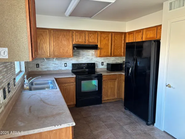 a kitchen with granite countertop wooden cabinets and a refrigerator