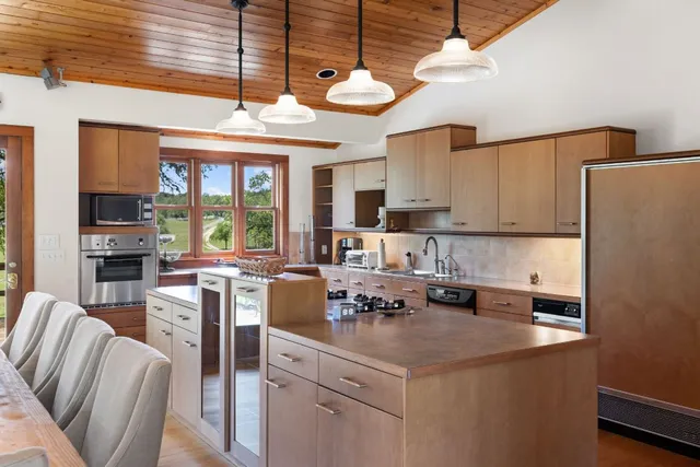 a kitchen with stainless steel appliances granite countertop a stove refrigerator a sink dishwasher and white cabinets next to a window